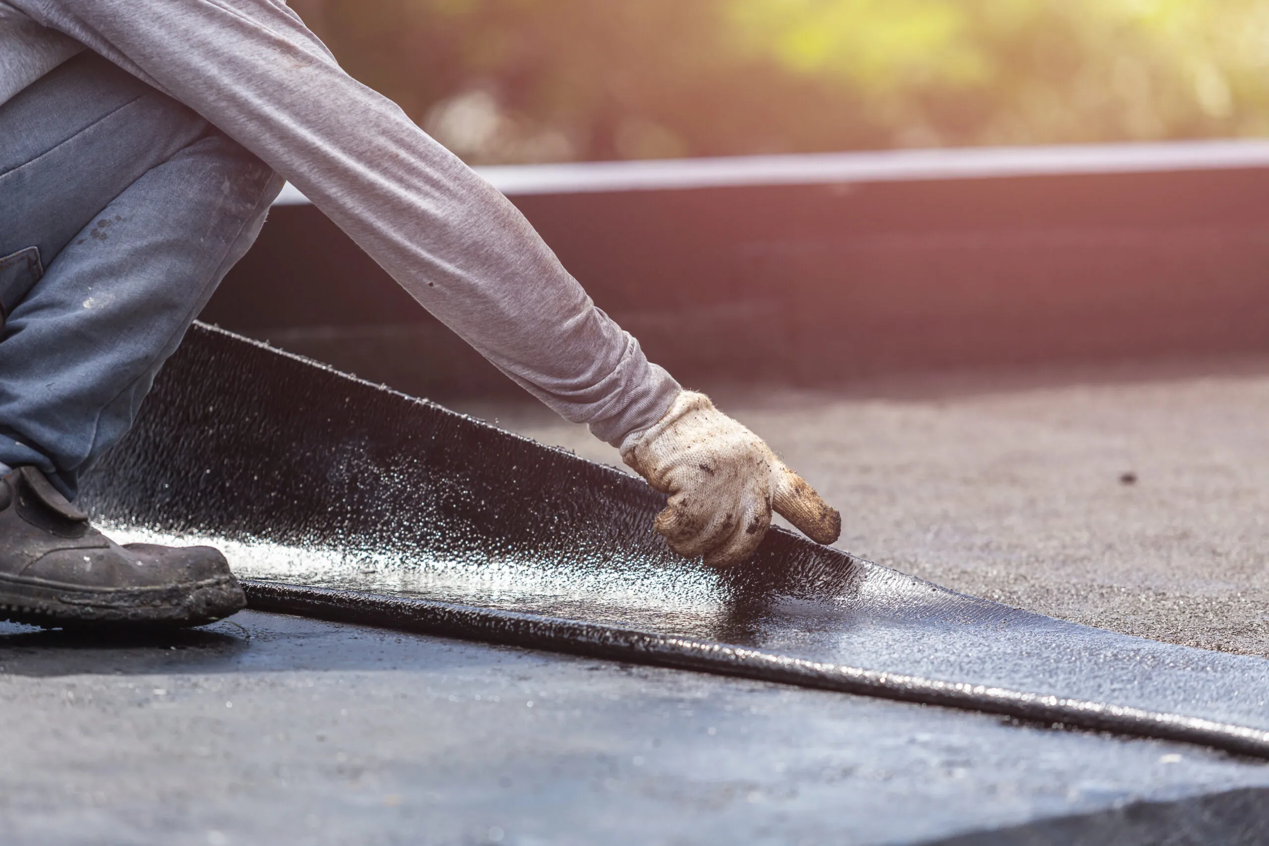 Group of worker installing tar foil on the rooftop of building. Waterproof system by gas and fire torching.